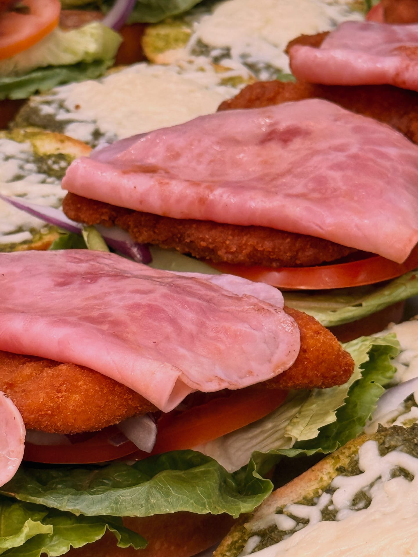 A sandwich stacked with ham and salad