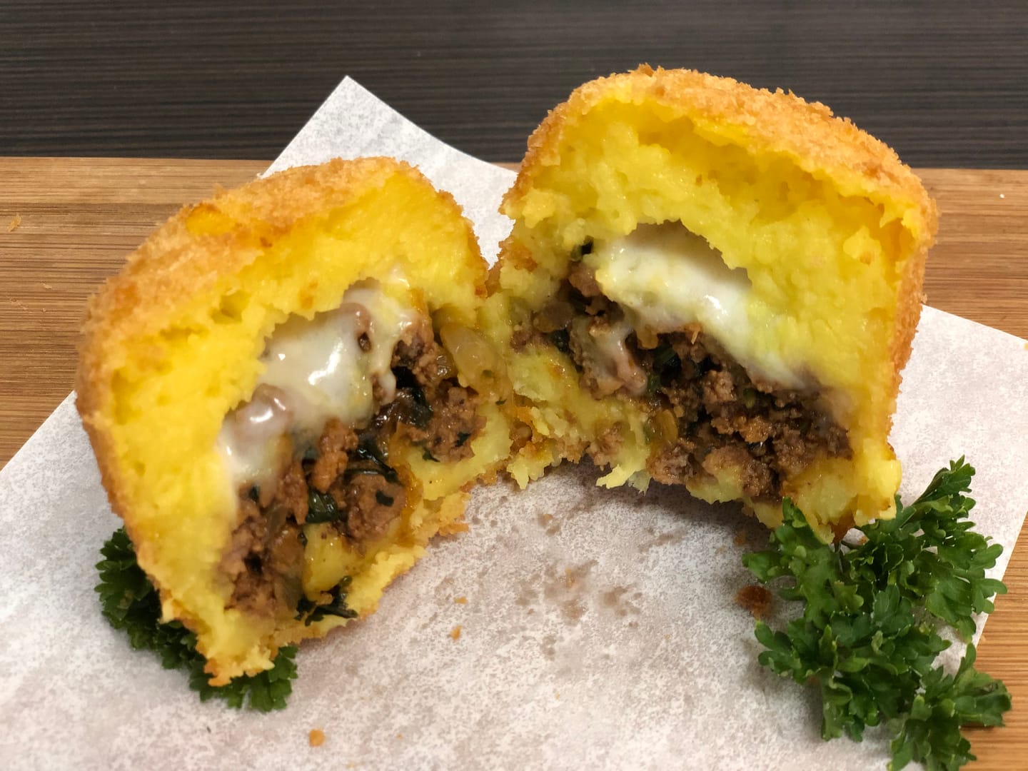 An empanada cut open, cheese and filling showing
